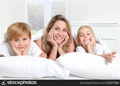 Mother and children laying in bed in the morning