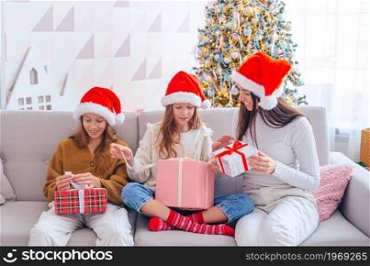 Mother and children on Christmas Holiday with gifts. Young mom with kids holding christmas presents
