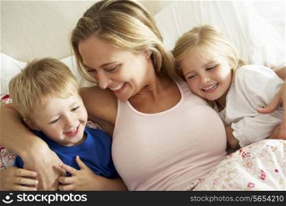 Mother And Children Relaxing Together In Bed