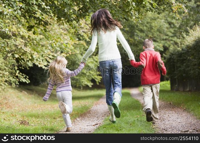Mother and children running on path outdoors (rear view)