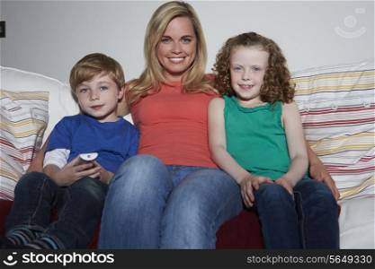 Mother And Children Sitting On Sofa Watching TV Together