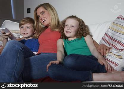 Mother And Children Sitting On Sofa Watching TV Together