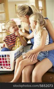 Mother And Children Sorting Laundry Sitting On Kitchen Counter