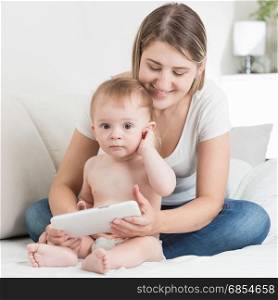 Mother and cute baby boy in diapers using tablet pc