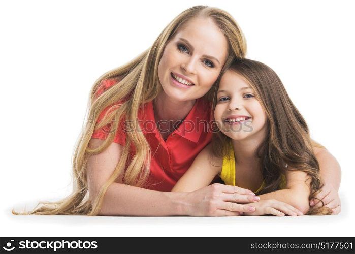 Mother and daugher on white. Happy smiling mother and daughter laying on floor, studio portrait isolated on white background