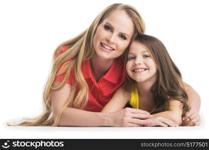 Mother and daugher on white. Happy smiling mother and daughter laying on floor, studio portrait isolated on white background