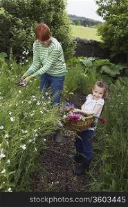 Mother and daughter (5-6) collecting flowers in garden