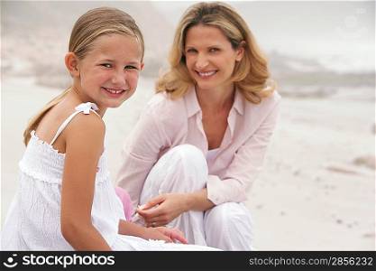 Mother and daughter (7-9) sitting on beach portrait