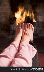 Mother and daughter&acute;s Feet warming at a fireplace