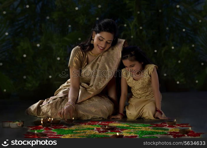 Mother and daughter arranging diyas