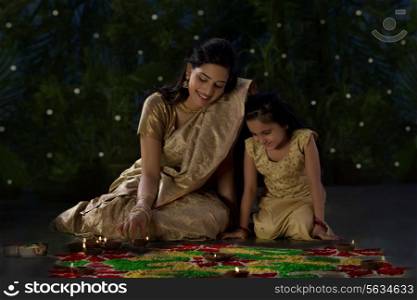 Mother and daughter arranging diyas