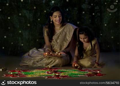 Mother and daughter arranging diyas