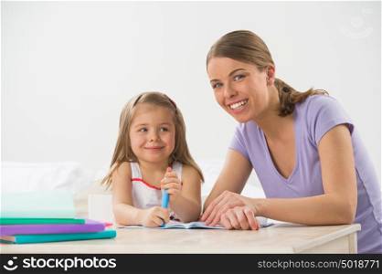 Mother and daughter at home. Mom teachs little girl to draw and write