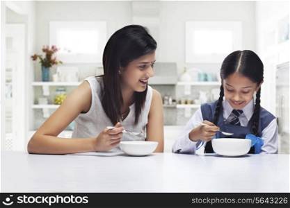 Mother and daughter at table eating breakfast