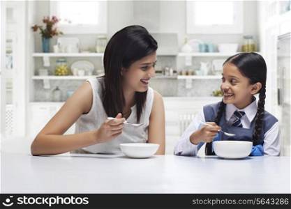 Mother and daughter at table eating breakfast