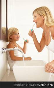 Mother And Daughter Brushing Teeth In Bathroom Together