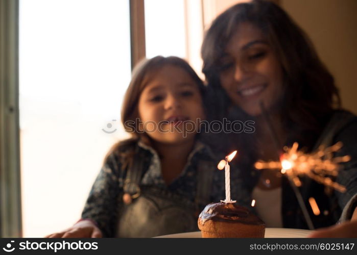 Mother and daughter celebrating birthday with cupcake and sparklers