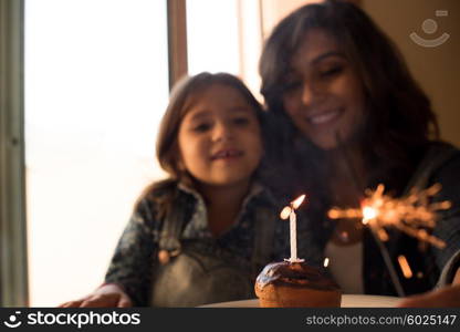 Mother and daughter celebrating birthday with cupcake and sparklers