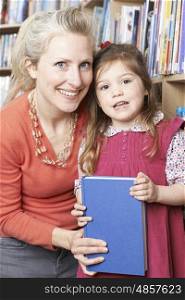 Mother And Daughter Choosing Book From Library Shelf