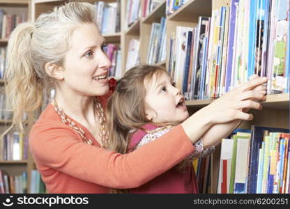 Mother And Daughter Choosing Book From Library Shelf