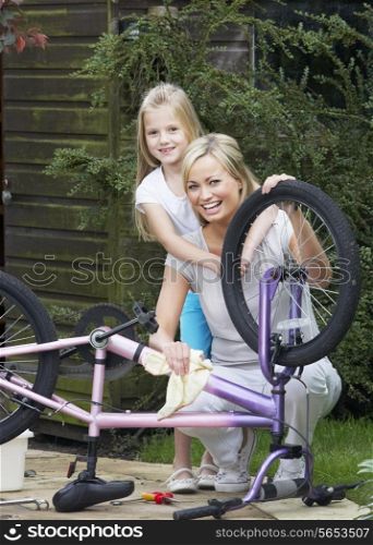 Mother And Daughter Cleaning Bike Together