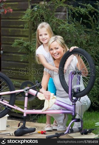 Mother And Daughter Cleaning Bike Together
