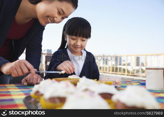 Mother and daughter decorating cupcakes