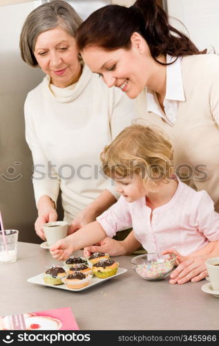 Mother and daughter decorating cupcakes sprinkles happy together at home