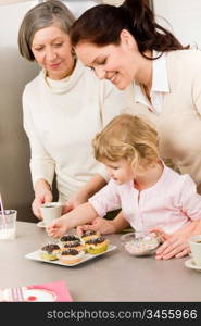 Mother and daughter decorating cupcakes sprinkles happy together at home