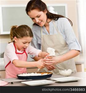 Mother and daughter decorating pie with whipped cream