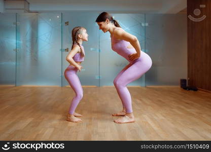 Mother and daughter doing exercise in gym, fitness workout. Mom and little girl in sportswear, joint training in sportclub. Mother and daughter doing exercise in gym