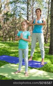 Mother and daughter doing exercise outdoors - mother teaching her daughter how to do exercises