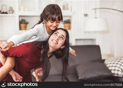 Mother and daughter doing piggyback in funny gesture emotion at home. Young sister playing with girl in good relationship lifestyles relaxation. Happy family and home sweet home theme concept