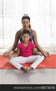 Mother and daughter doing yoga and meditating