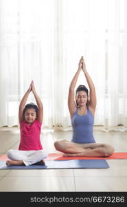 Mother and daughter doing yoga and meditating