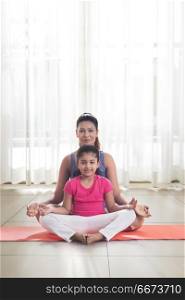 Mother and daughter doing yoga and meditating