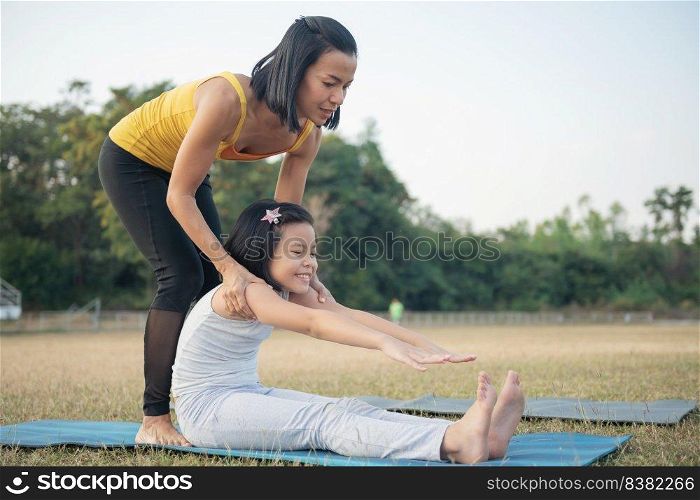 Mother and daughter doing yoga. woman and child training in the park. outdoor sports. healthy sport lifestyle,  sitting in paschimottanasana exercise, seated forward bend pose.