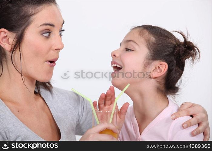 Mother and daughter drinking from the same glass