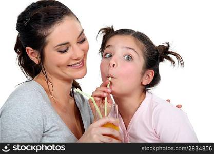 Mother and daughter drinking through straws