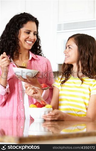 Mother and daughter eating cereal and fruit