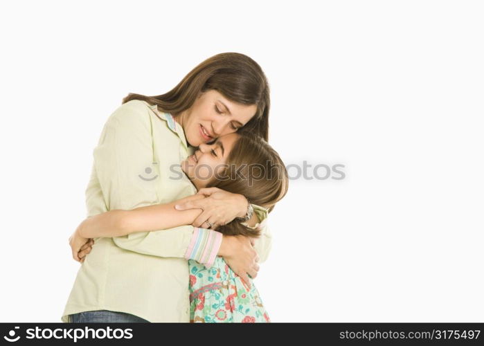 Mother and daughter embracing standing against white background.