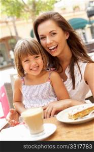 Mother And Daughter Enjoying Cup Of Coffee And Piece Of Cake In CafZ