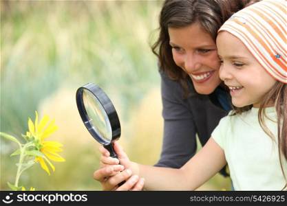 Mother and daughter examining a flower using a magnifying glass