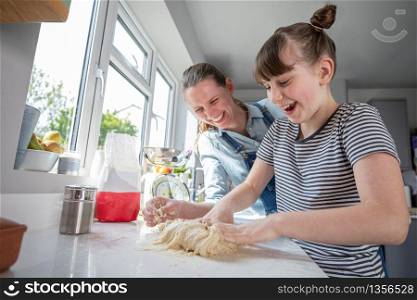 Mother And Daughter Having Fun In Kitchen At Making Dough For Home Baked Bread Together
