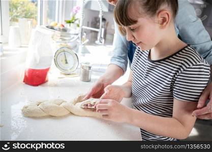 Mother And Daughter Having Fun In Kitchen At Plaiting Dough For Home Baked Bread Together
