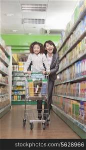 Mother and Daughter Having Fun in Supermarket, Pushing Cart