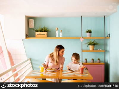 Mother and daughter having good time during breakfast with fresh squeezed juices in the cafe