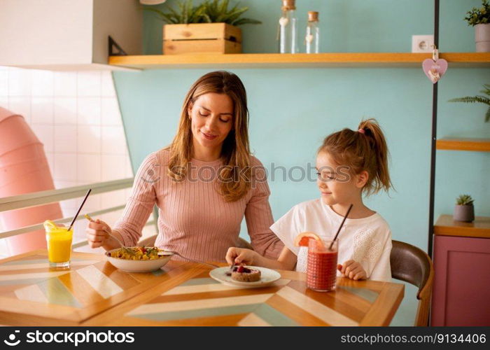 Mother and daughter having good time during breakfast with fresh squeezed juices in the cafe