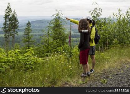 Mother and daughter hiking on mountain trail during summer