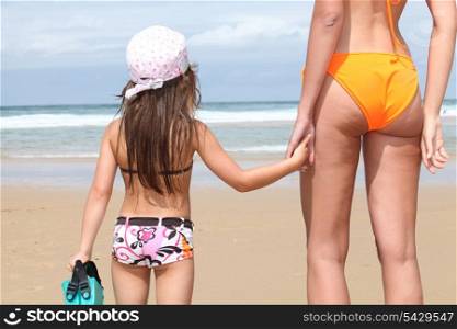 Mother and daughter holding hands on a sandy beach
